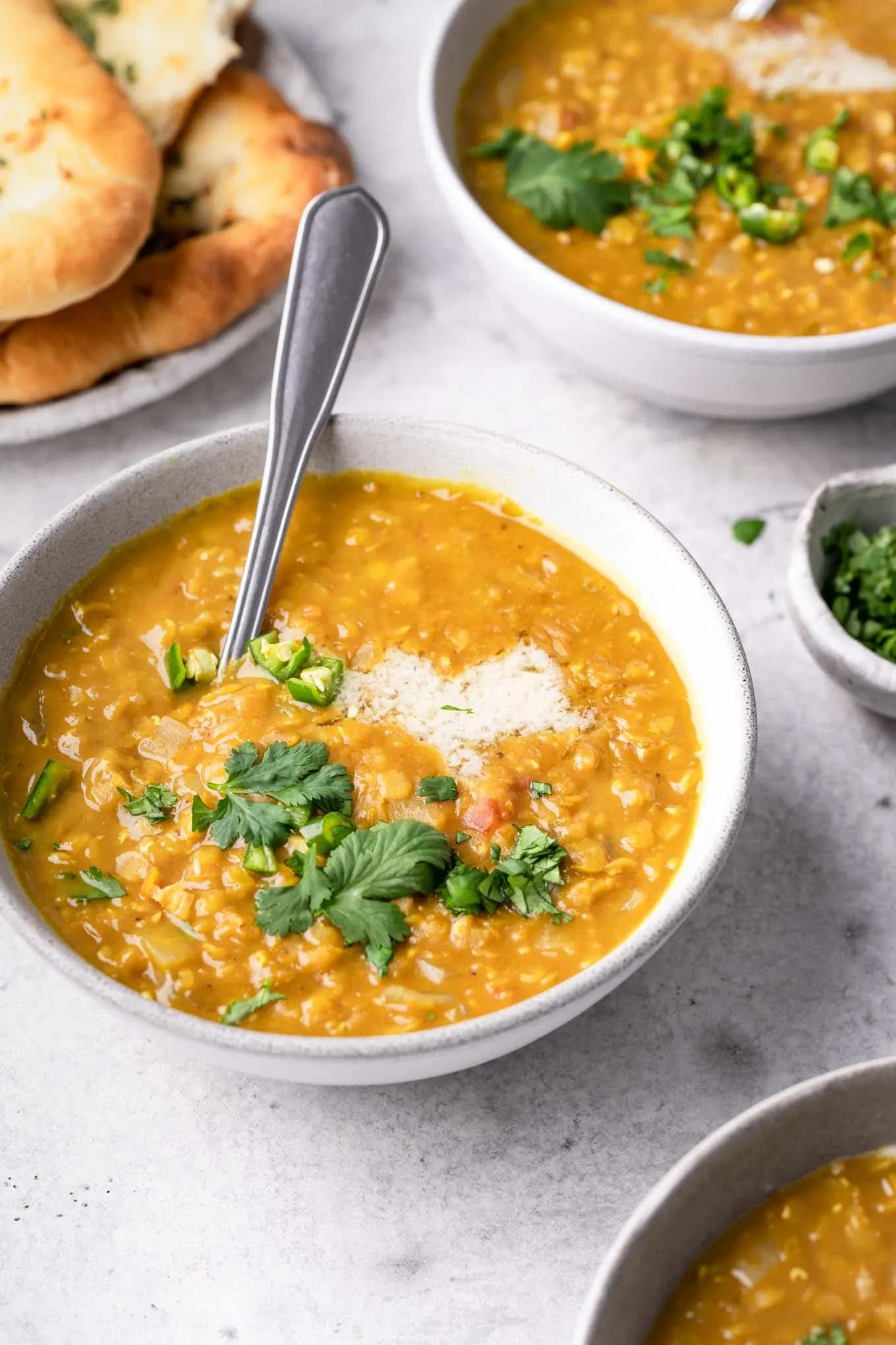 tamarind red lentil soup served in bowls with garlic naan
