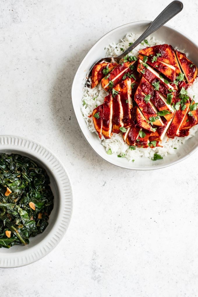 a bowl of barbecue tofu and rice, with a serving of collard greens