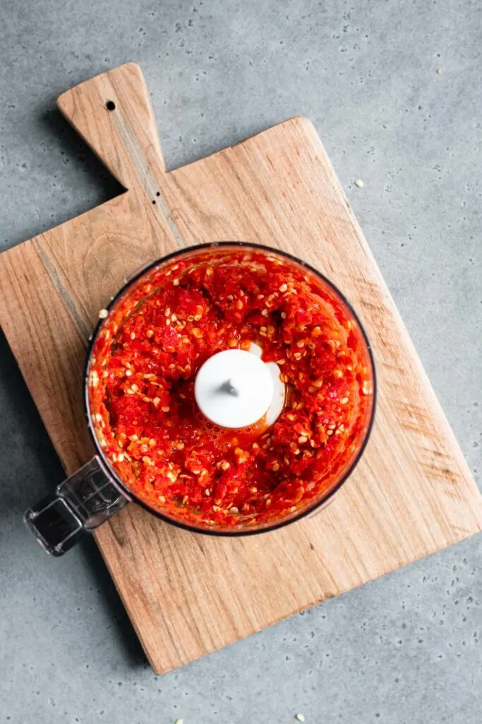 chili's chopped in mini-food processor sitting on a cutting board