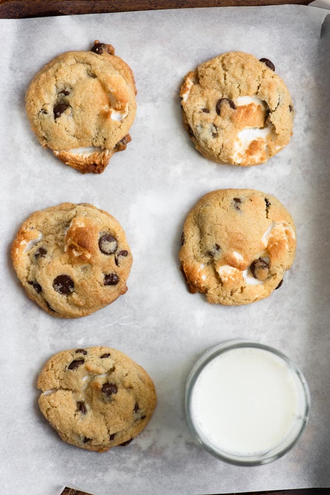 vegan chocolate chip marshmallow cookies on a baking tray with a glass of oat milk