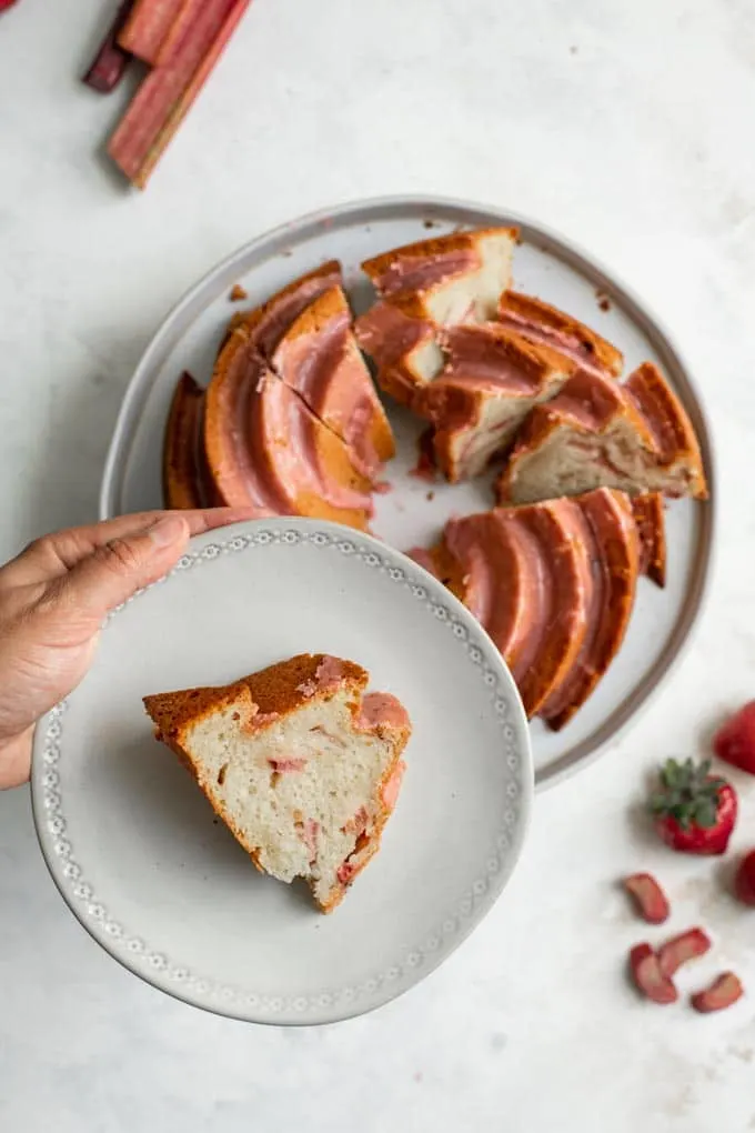 a slice of cake held over the rest of the almond rhubarb bundt cake