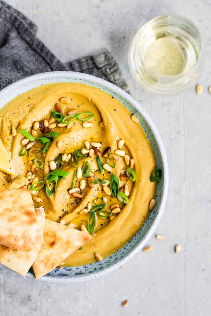 favosalata, a mediterranean dip made with yellow split peas, garnished with extra virgin olive oil, toasted pine nuts, and scallion greens. Served with flatbread and a glass of white wine.