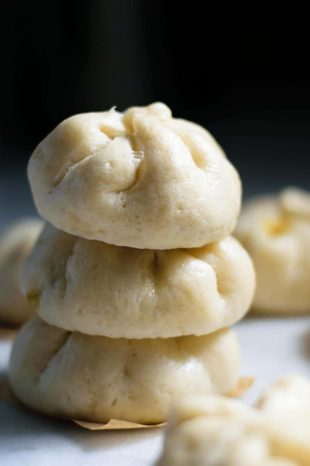 vegan curry seitan steamed buns, stacked 3 high with more in foreground and background