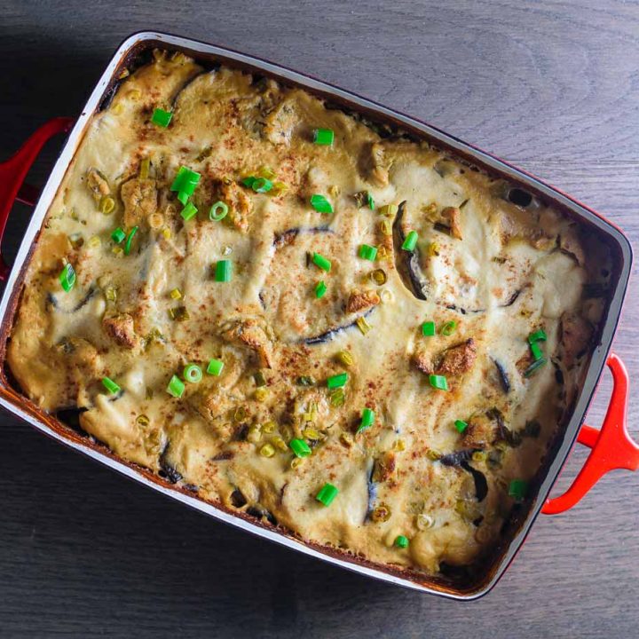 the vegan cheesy eggplant casserole in a red baking dish on a wooden background