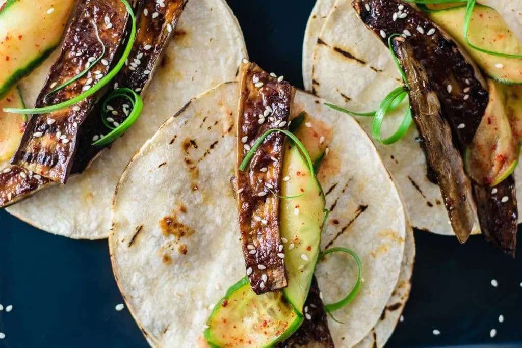 prepared miso-glazed eggplant tacos (nasu dengaku tacos) with marinated cucumbers and scallions, close up