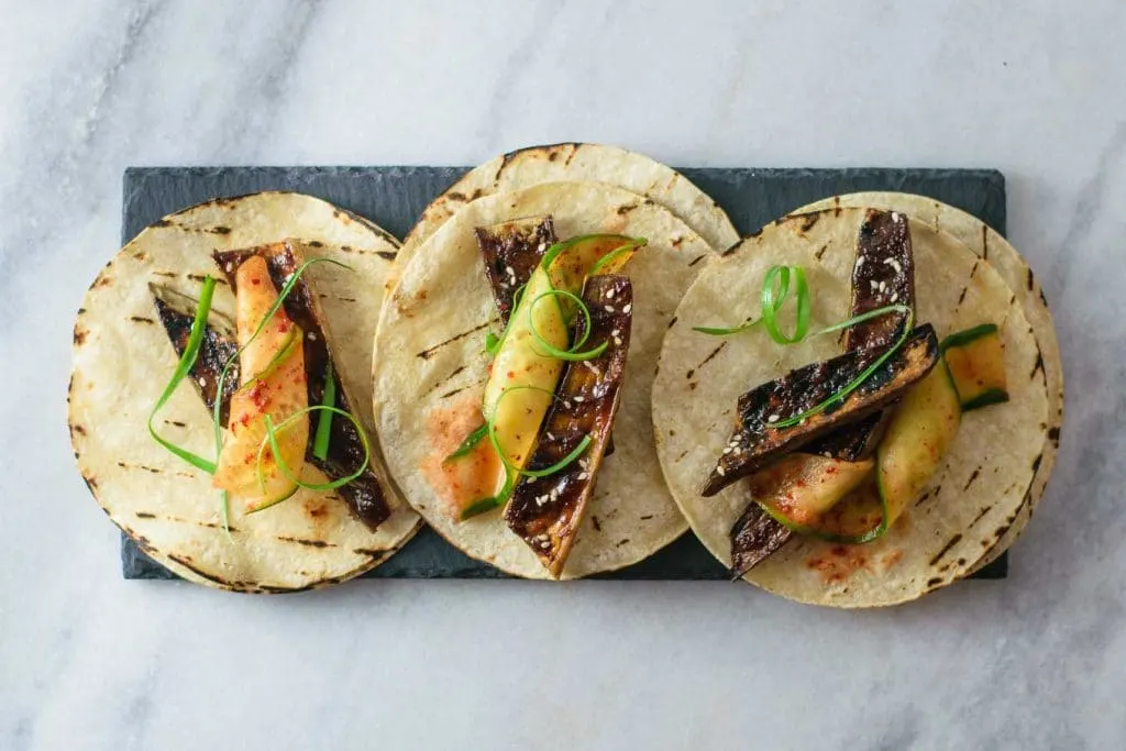 miso glazed eggplant tacos with chili marinated cucumber and scallions on slate