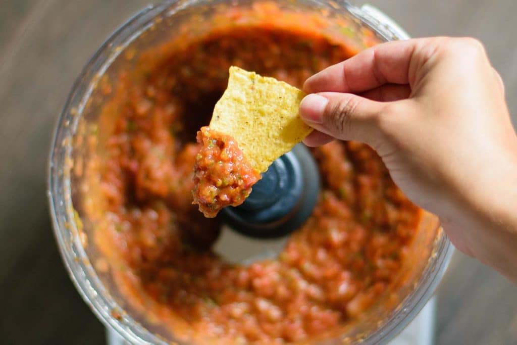 chip dipped into the spicy roasted tomato salsa over the food processor