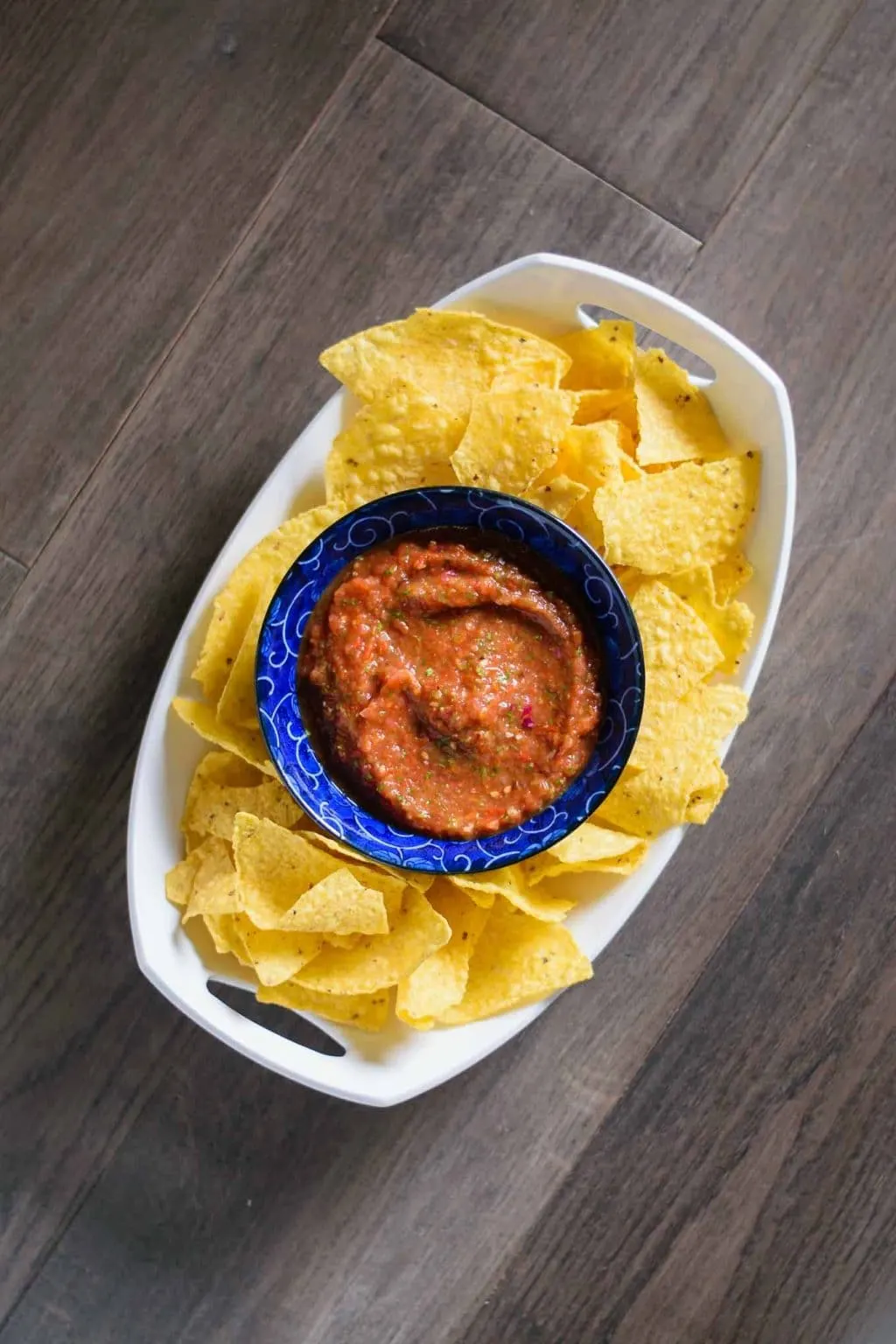 spicy roasted tomato salsa in bowl surrounded with tortilla chips