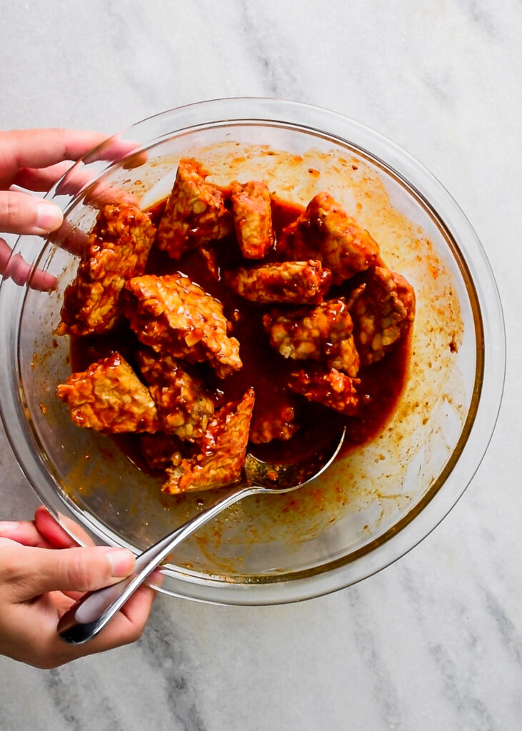 tossing tempeh in gochujang marinade