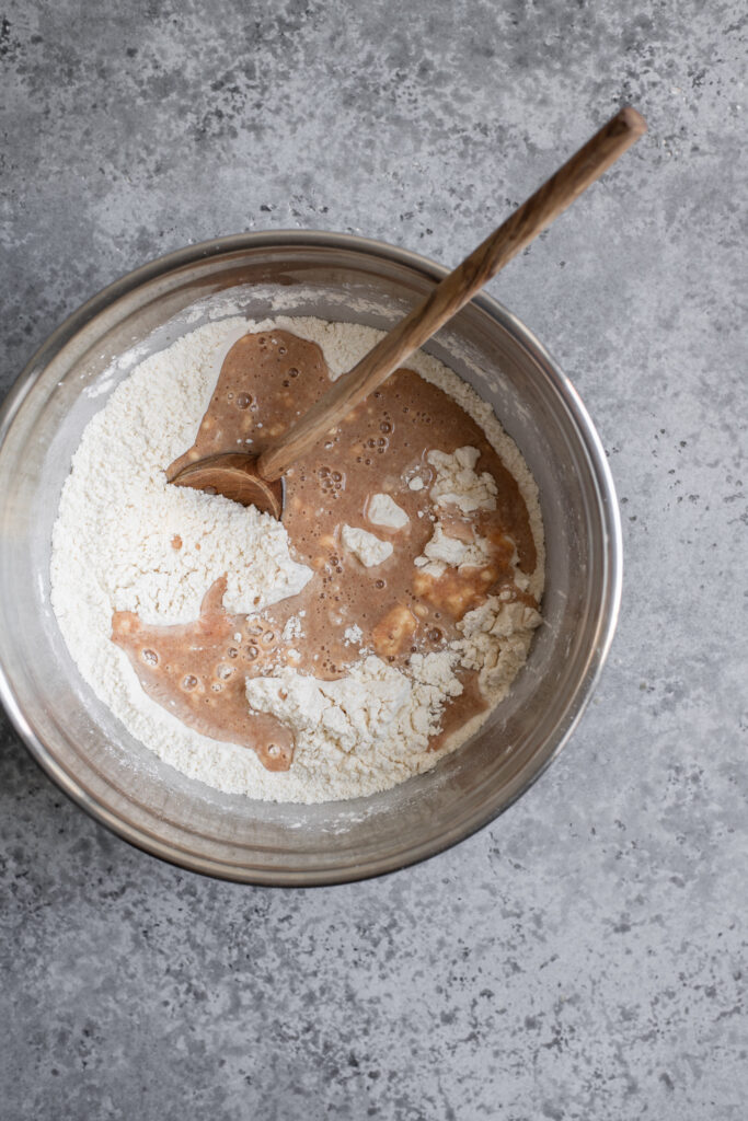 wet and dry ingredients for cinnamon roll dough combined in a mixing bowl