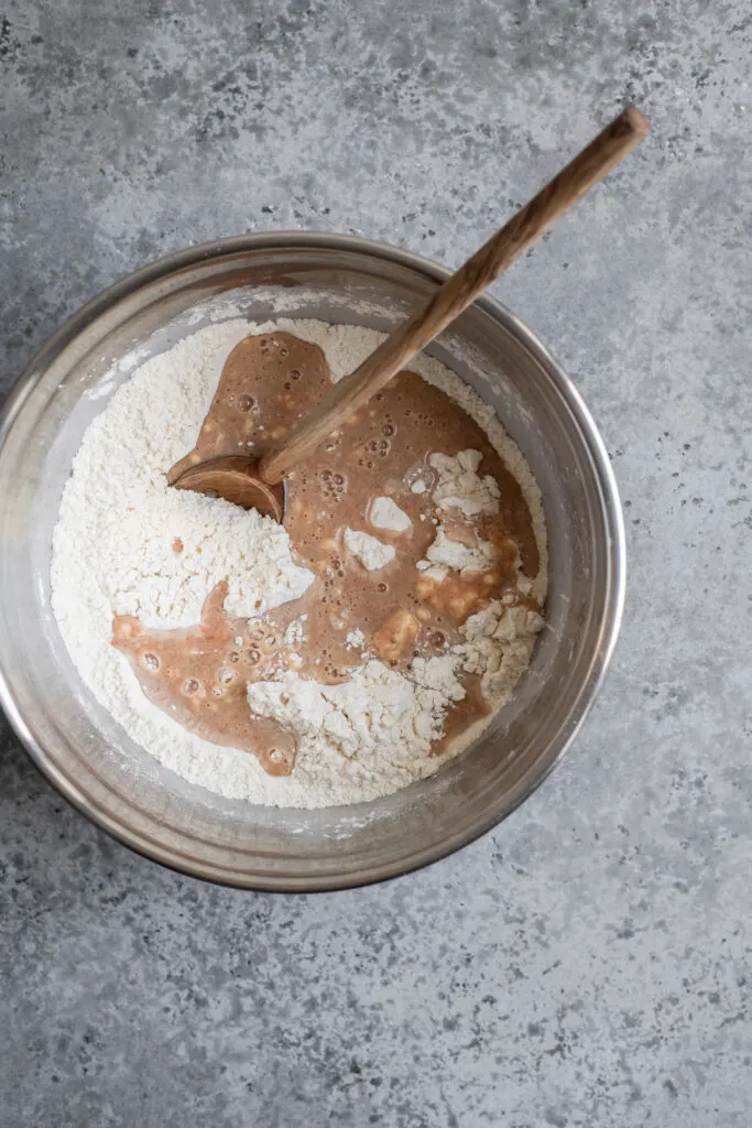 wet and dry ingredients for cinnamon roll dough combined in a mixing bowl