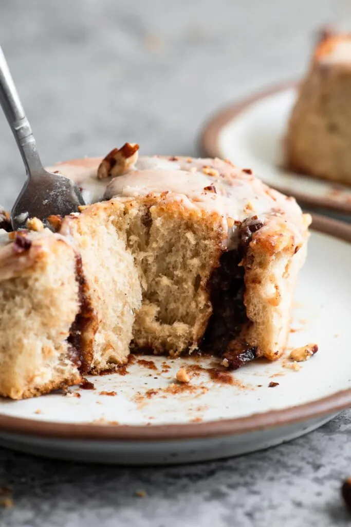 a cut into cinnamon bun with a fork picking up a soft piece