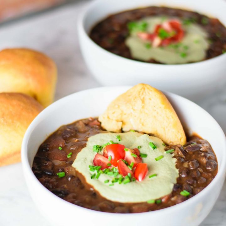 black bean soup with pepita cream, garnished with diced cherry tomatoes and chives and served with sweet potato rolls