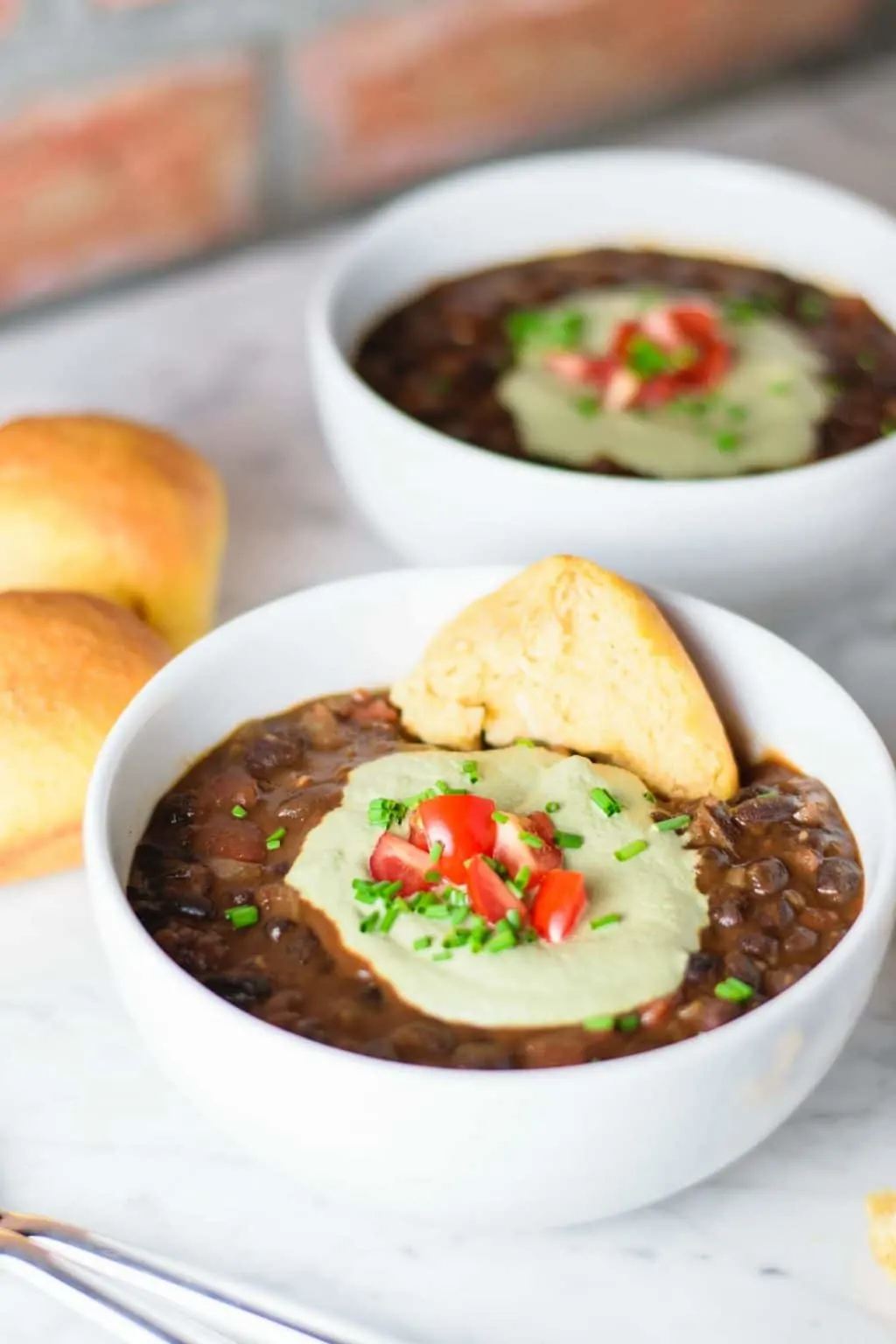 black bean soup with pepita cream, garnished with diced cherry tomatoes and chives and served with sweet potato rolls