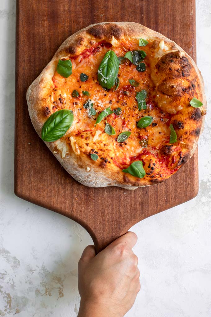 vegan cheese pizza on a cutting board being placed on a table