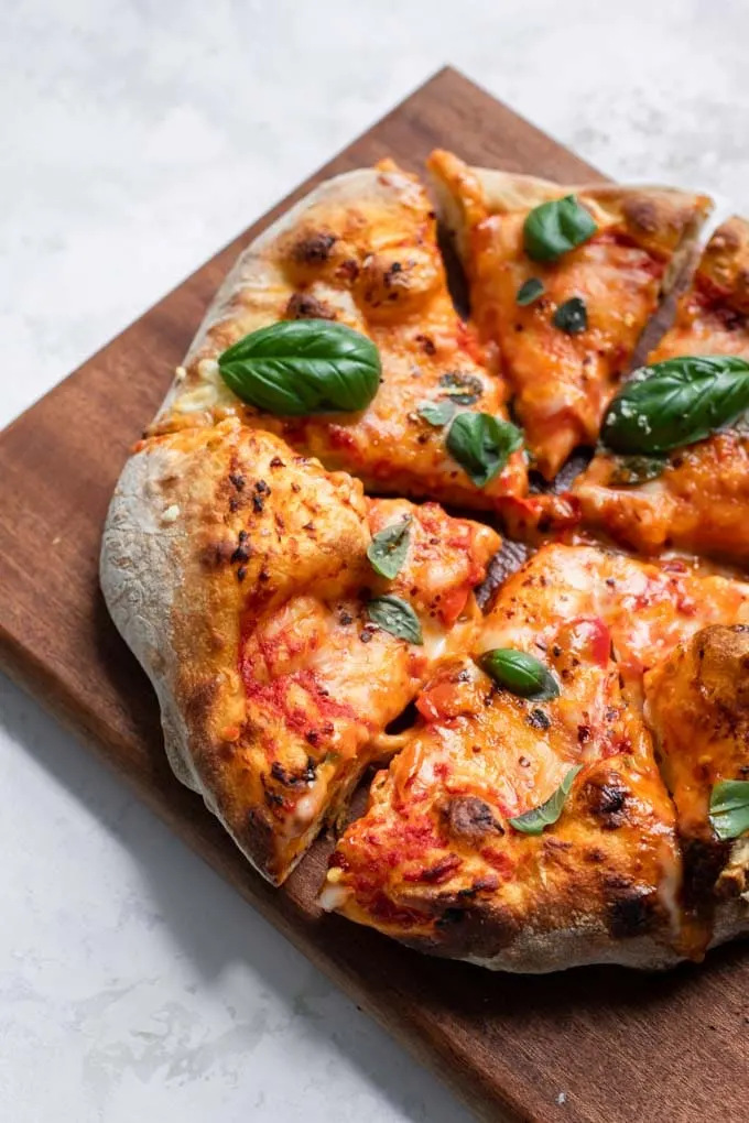 vegan cheese pizza made with easy overnight pizza dough on a cutting board cut into slices