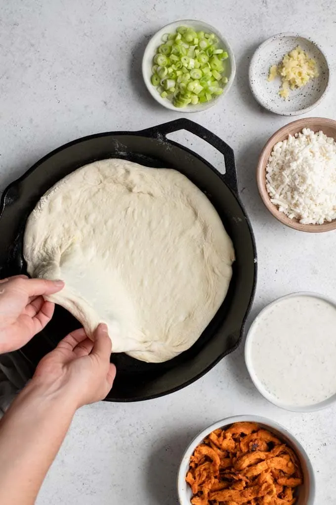 stretching dough into cast iron skillet