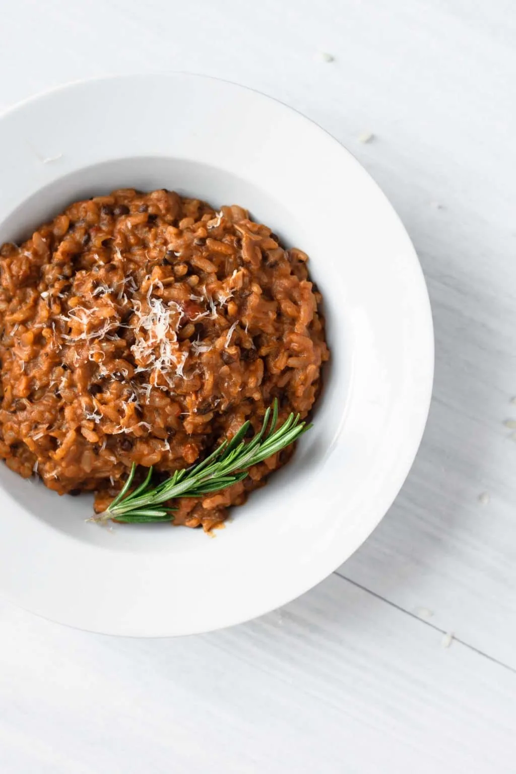 vegan risotto bolognese served with vegan parmesan and fresh rosemary sprig