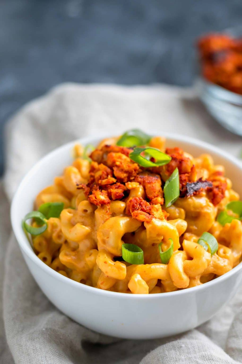 Vegan chipotle mac and cheese with spicy tempeh crumbles, garnished with scallion greens