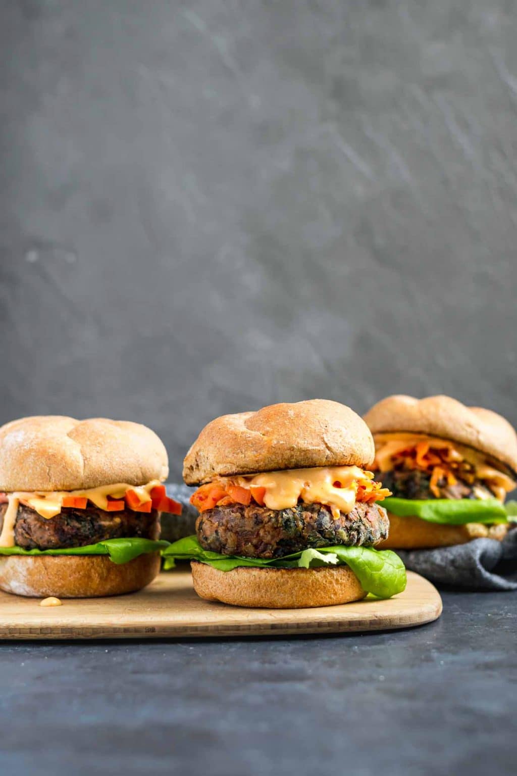 Vegan gochujang bean burgers topped with kimchi, fermented carrots, and gochujang mayo.