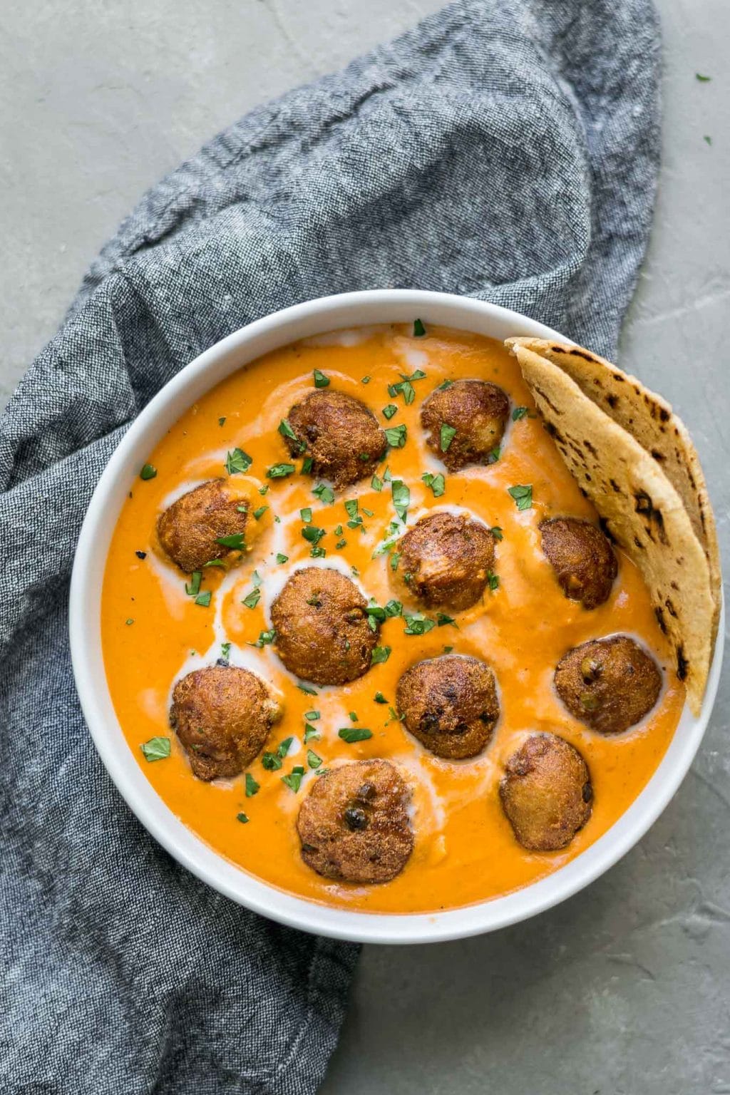 vegan malai kofta with a piece of chapati tucked into the bowl