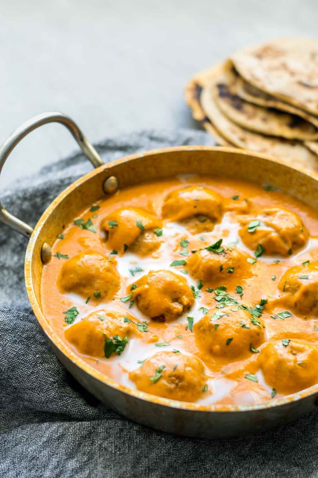 Vegan malai kofta in a kadai pot viewed from an angle with chapati in the background