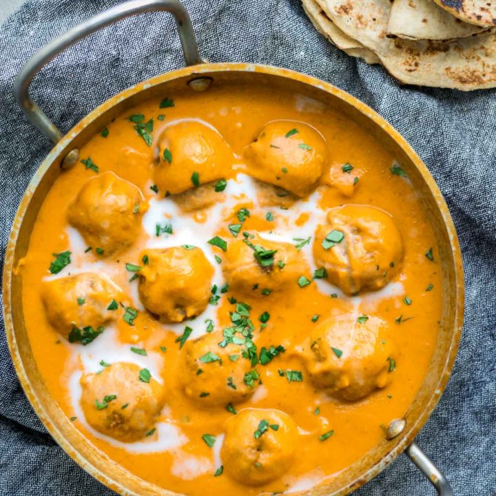 Vegan malai kofta (Indian dumplings in curry tomato cream sauce) in a kadai pot served with chapati