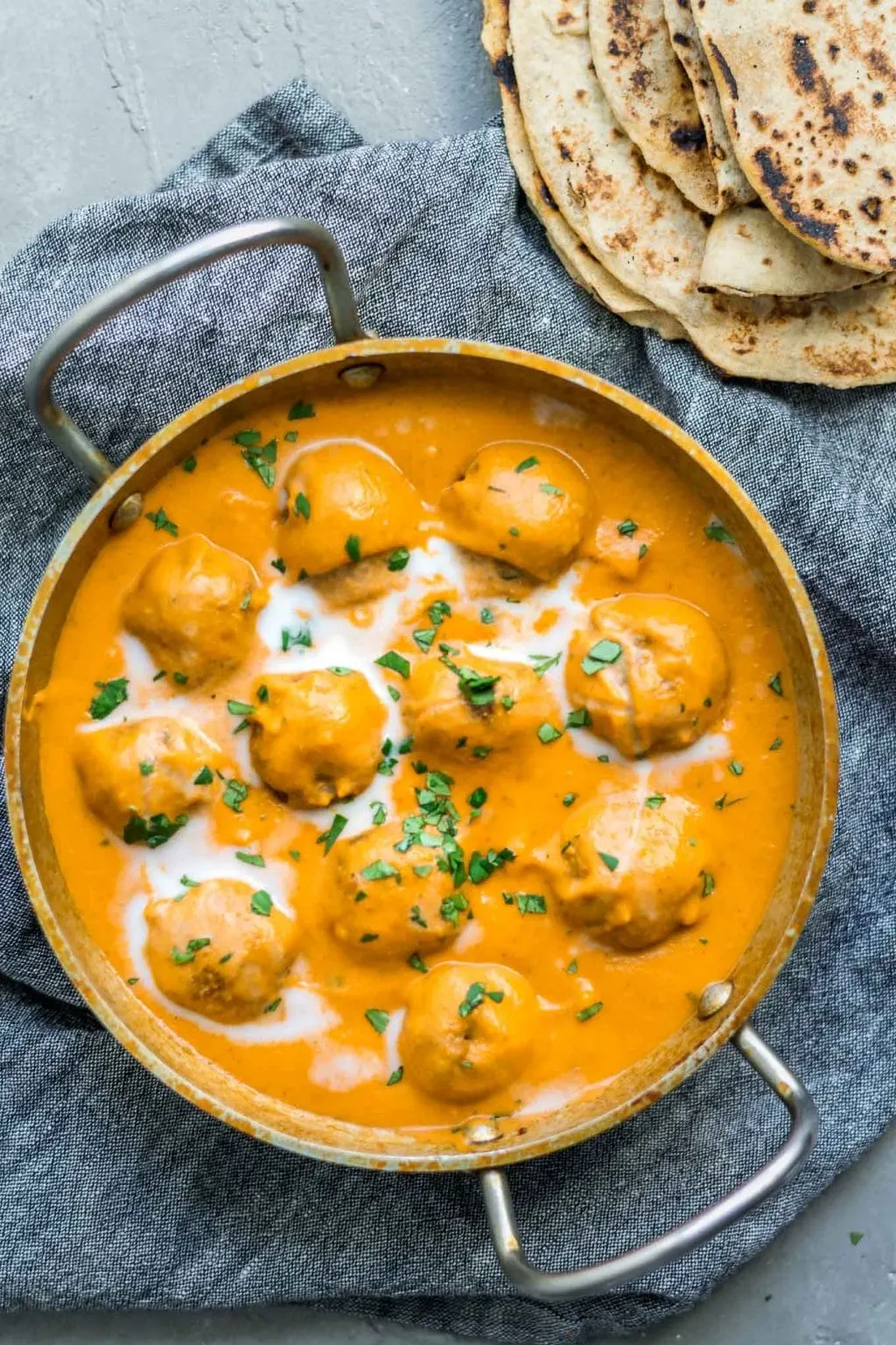 Vegan malai kofta (Indian dumplings in curry tomato cream sauce) in a kadai pot served with chapati