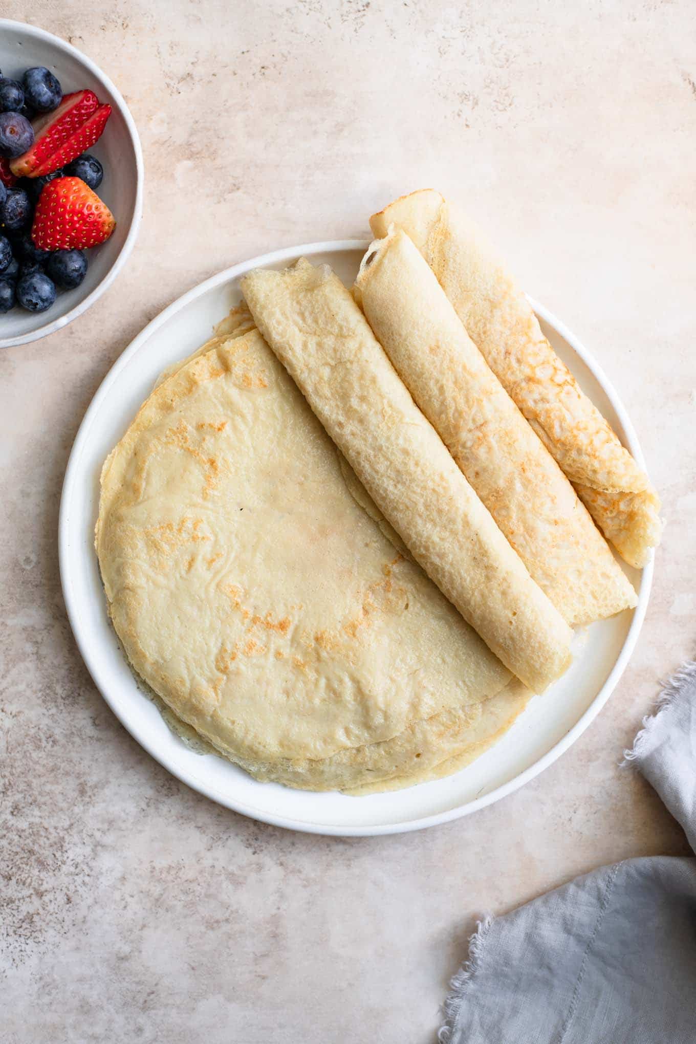 easy vegan crepes cooked and stacked with three rolled up