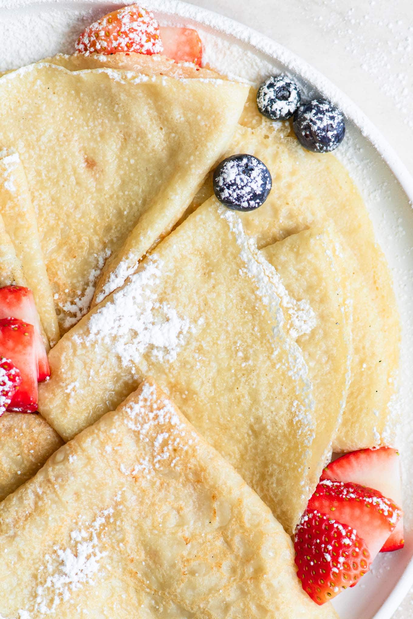 close up of easy vegan crepes folded into triangles and dusted with powdered sugar