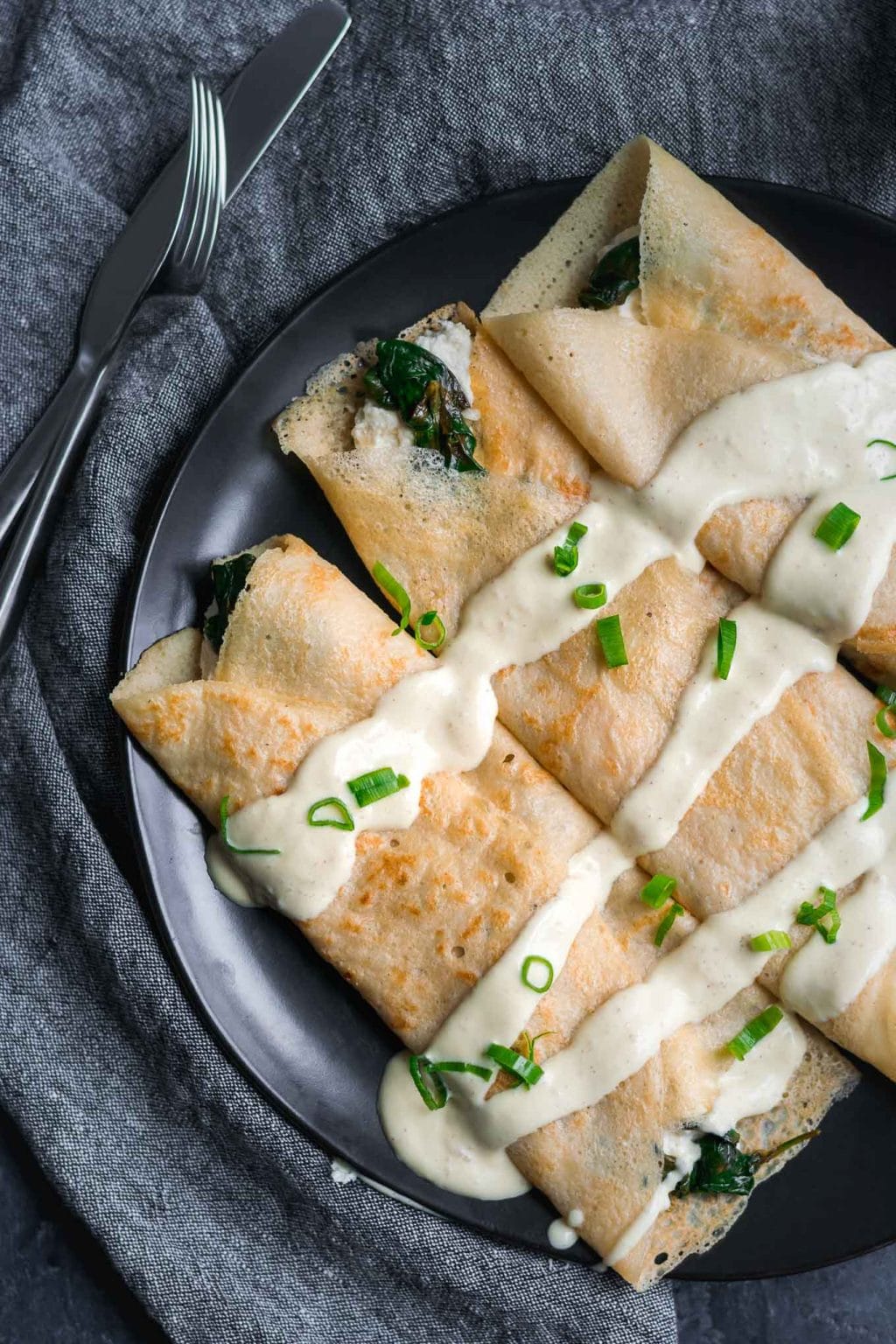 Savory crepes with almond cheese, sauteed spinach, and vegan hollandaise