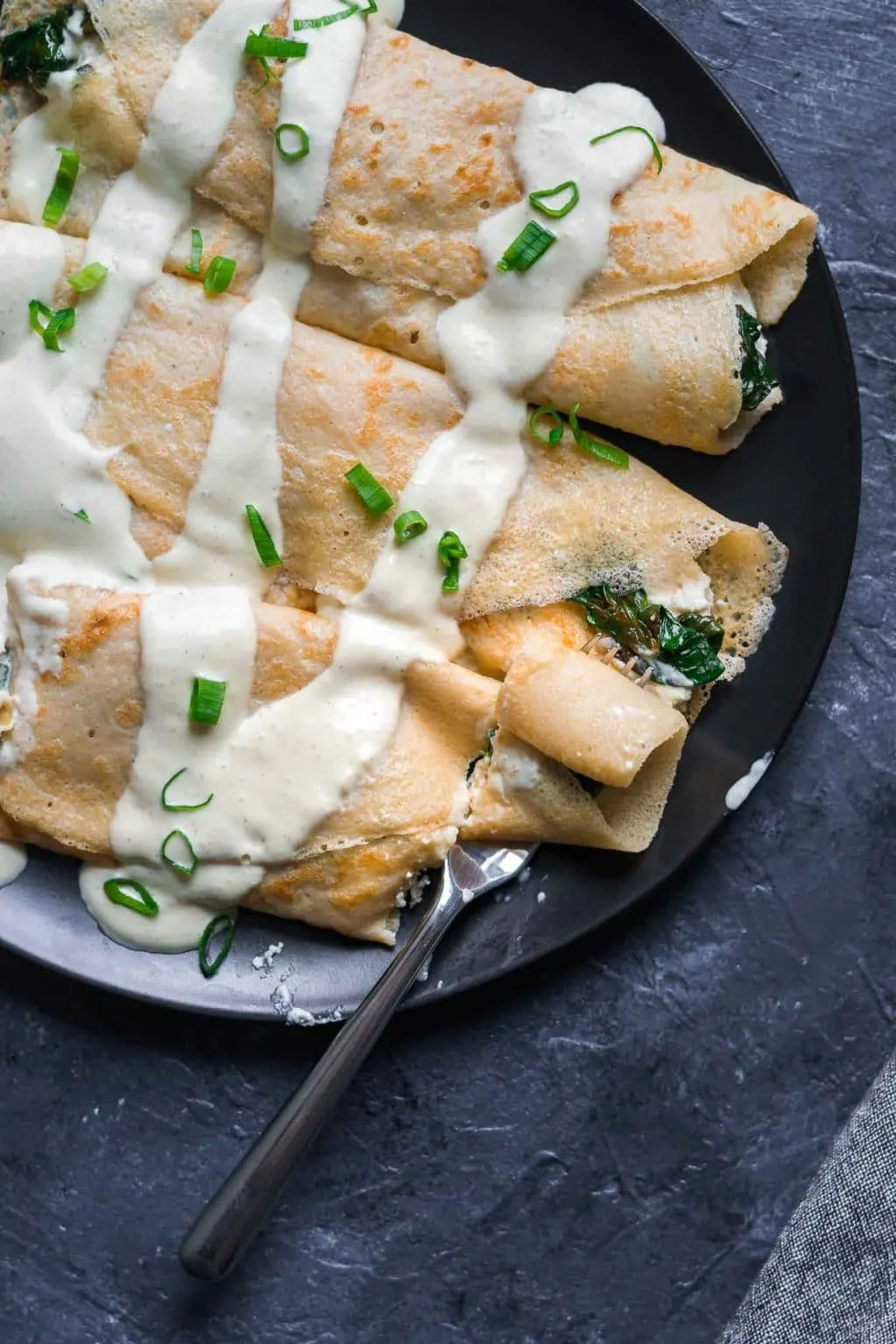 Savory crepes with almond cheese, sauteed spinach, and vegan hollandaise drizzled on top. Garnished with scallion greens.