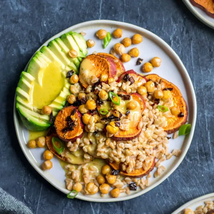 Roasted sweet potato and farro salad with garlicky chickpeas with sun dried tomatoes, avocado, and a lemon vinaigrette. Garnished with sliced scallion greens.