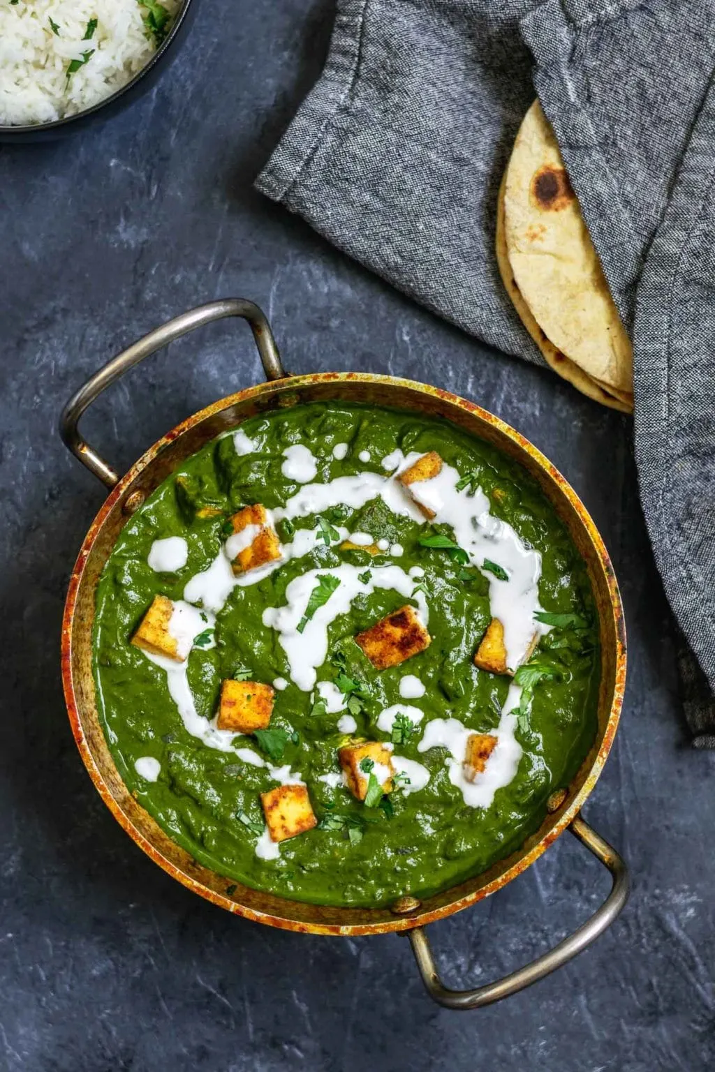 vegan palak tofu paneer with a drizzle of coconut milk and served with fresh chapati bread and basmati rice