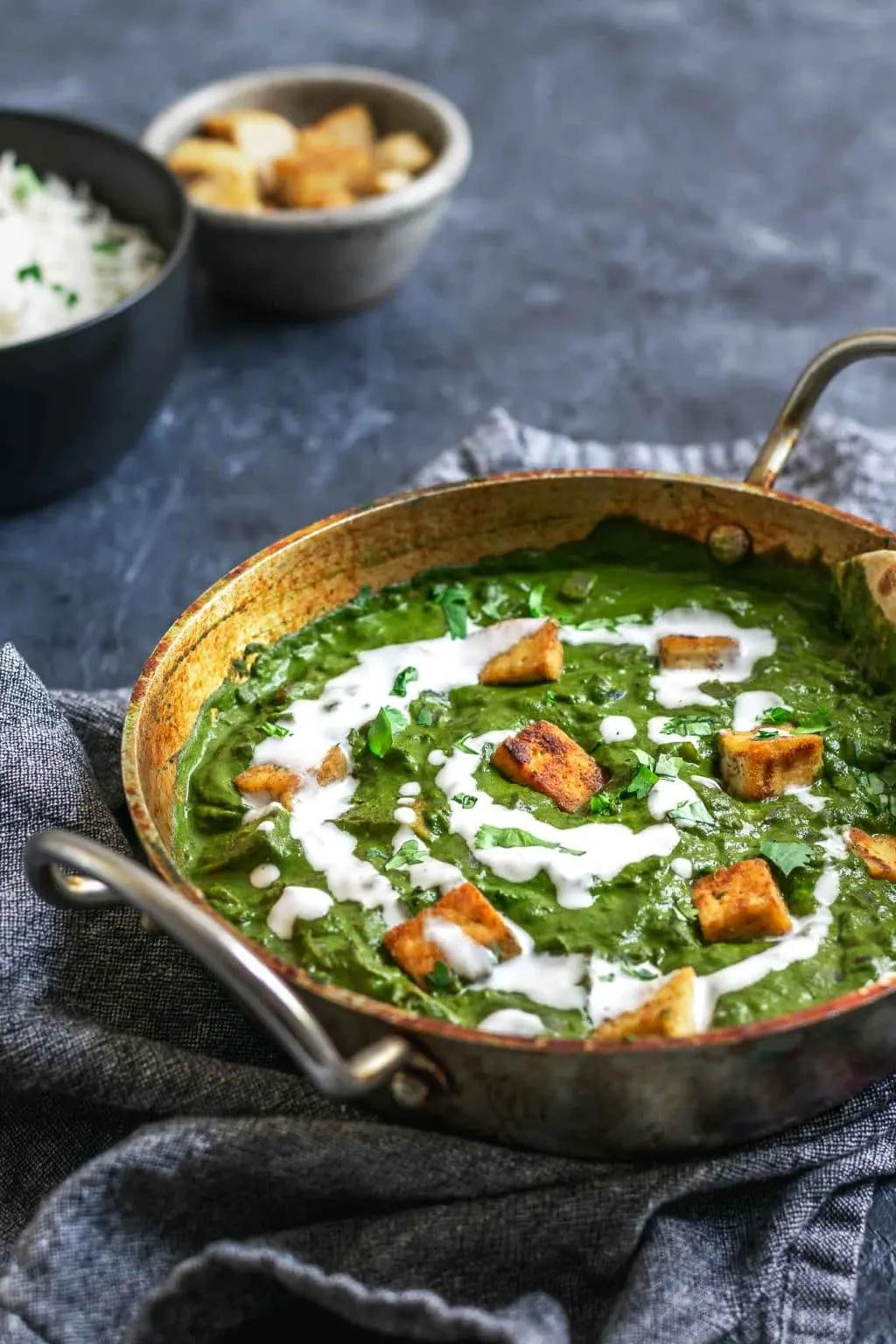 vegan palak tofu paneer with a drizzle of coconut milk and served with basmati rice and extra tofu paneer on the sie