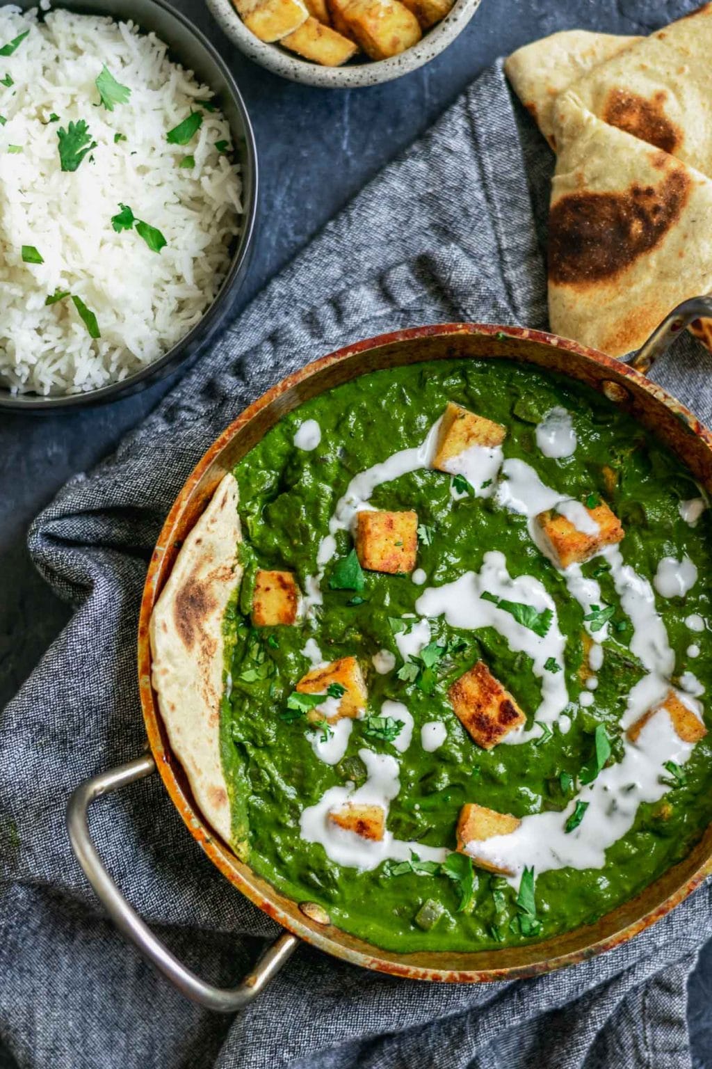 vegan palak tofu paneer with a drizzle of coconut milk and served with fresh chapati bread and basmati rice with extra tofu paneer on the side