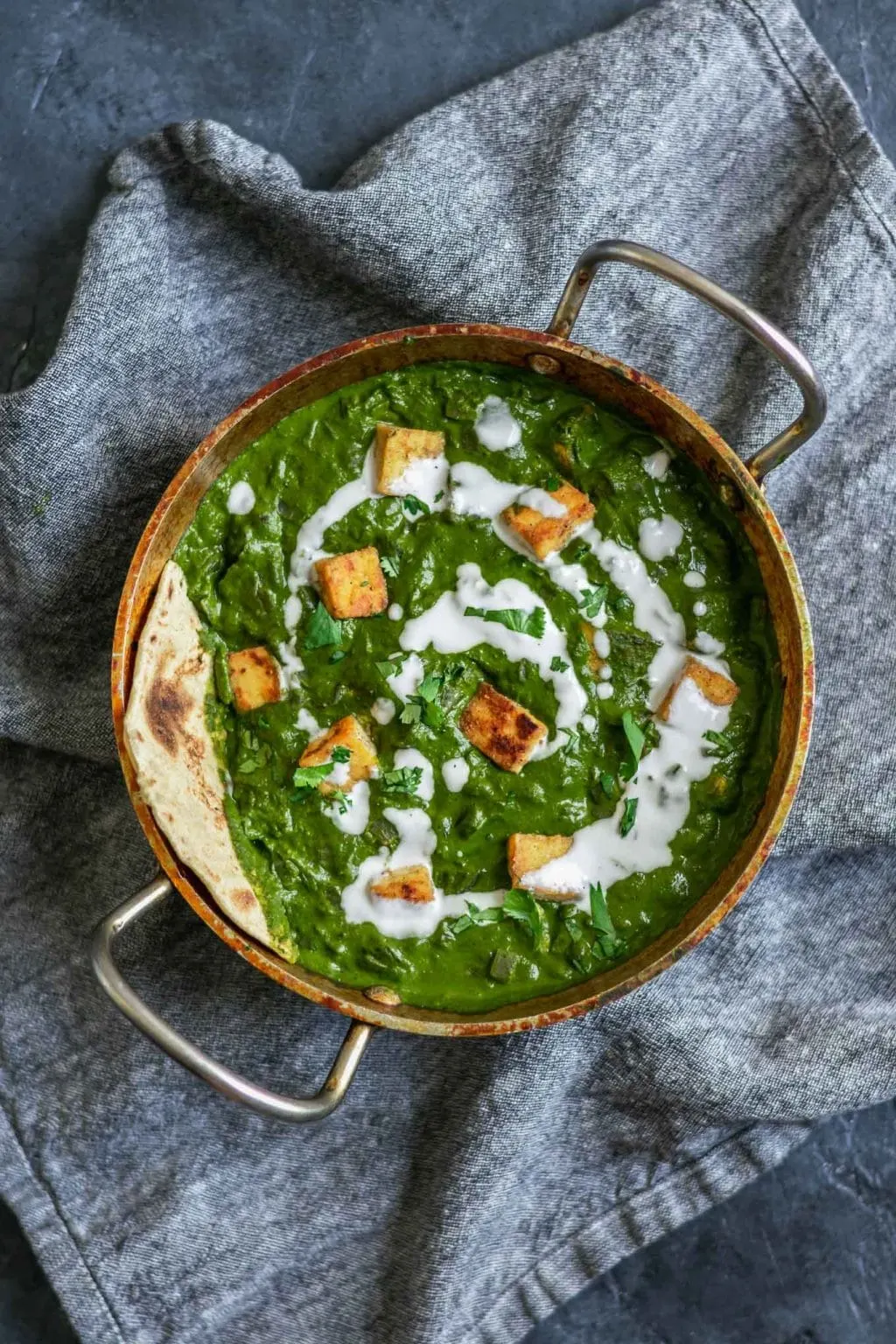 vegan palak tofu paneer with a drizzle of coconut milk and served with fresh chapati bread