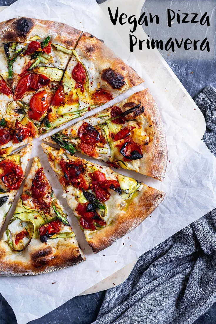 Vegan pizza primavera with ribboned zucchini and asparagus and burst cherry tomatoes with a garlic white sauce. | thecuriouschickpea.com #vegan #pizza