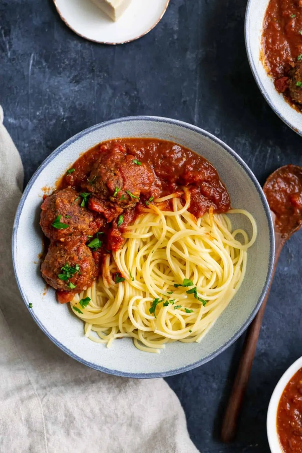 Spaghetti with roasted eggplant marinara and vegan lentil meatballs garnished with minced parsley. Overhead shot.