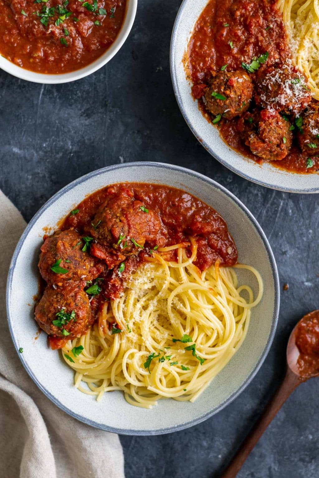 Spaghetti with roasted eggplant marinara and vegan lentil meatballs garnished with vegan parmesan and minced parsley