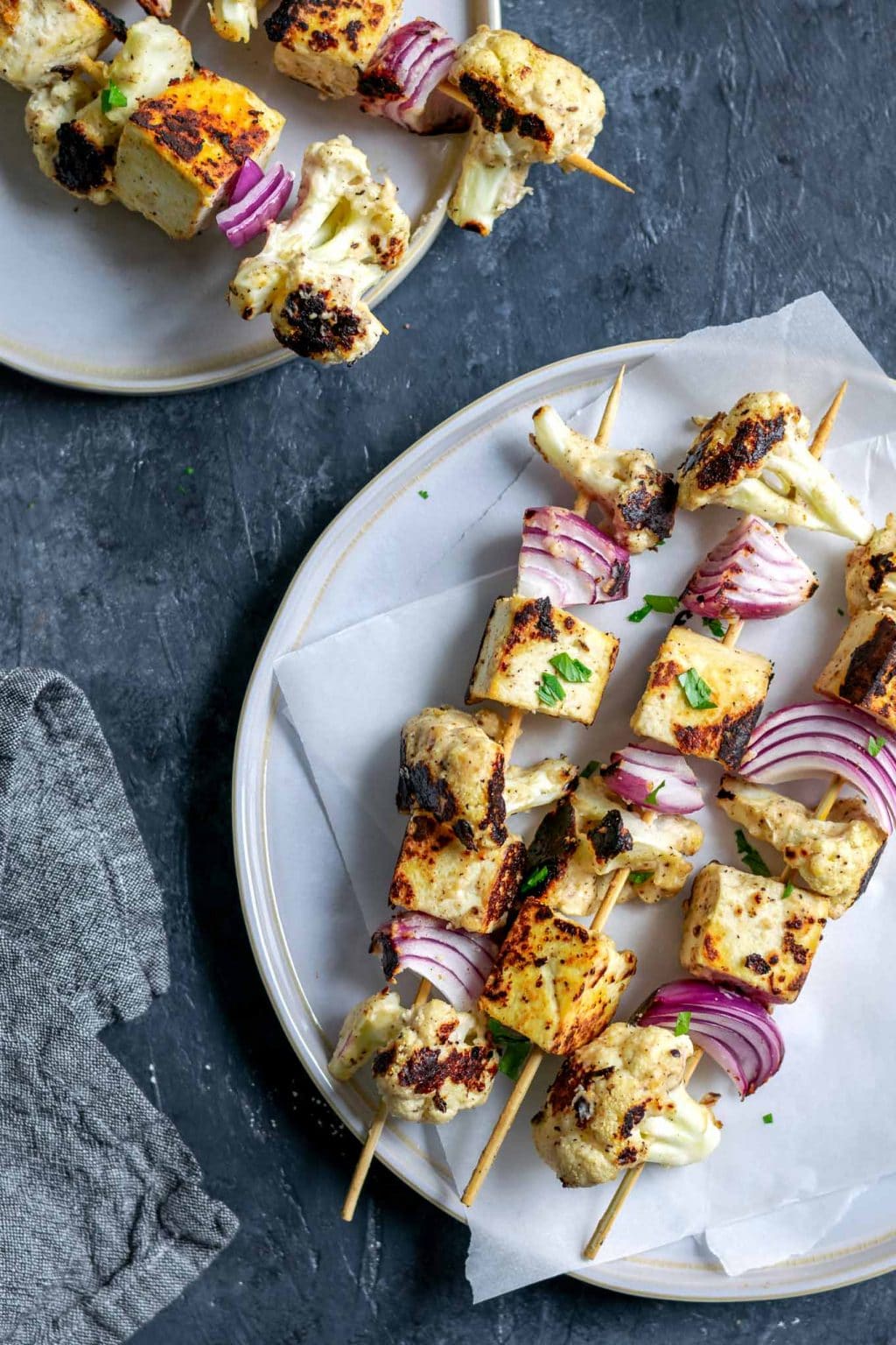 Afghan cauliflower and tofu tikka kebab skewers served on two plates