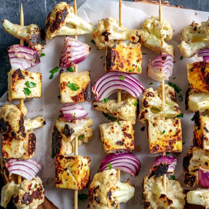 Afghan cauliflower and tofu tikka kebab skewers on a wooden platter