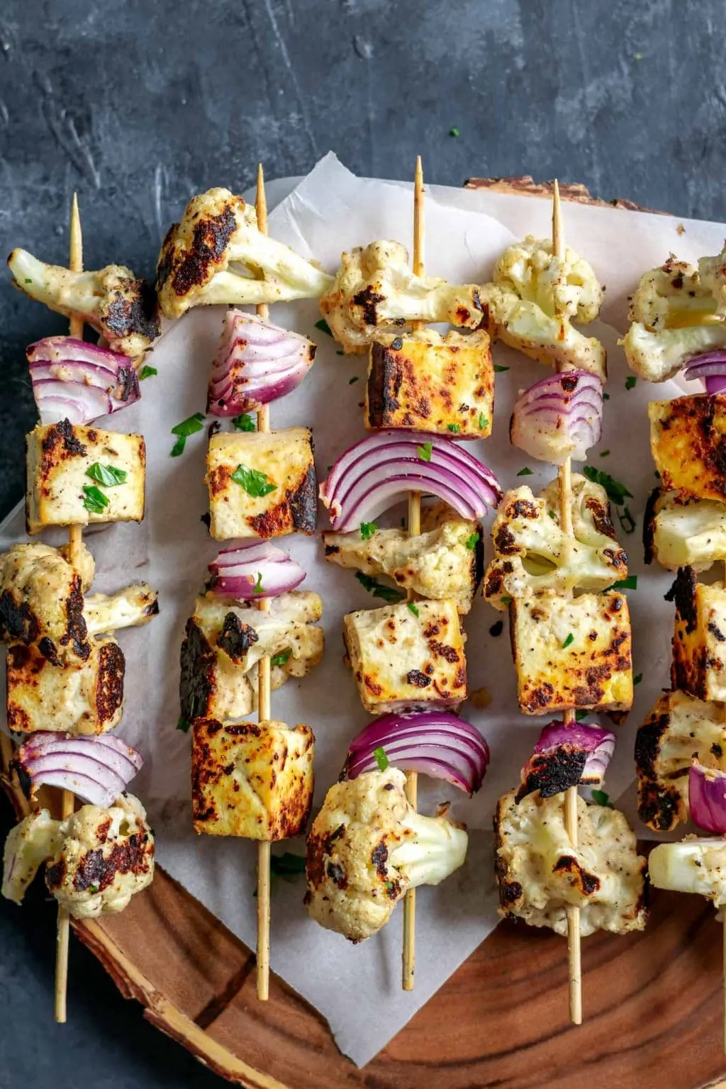 Afghan cauliflower and tofu tikka kebab skewers on a wooden platter