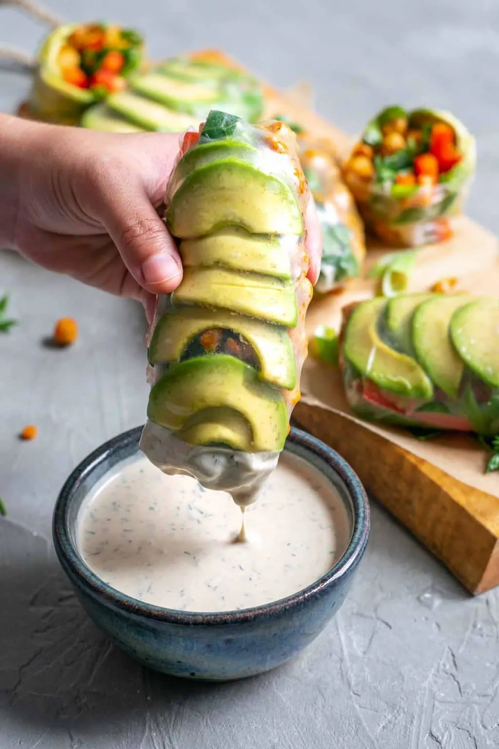 buffalo chickpea rice paper wraps with tahini ranch dip, with one wrap being dipped into the tahini ranch