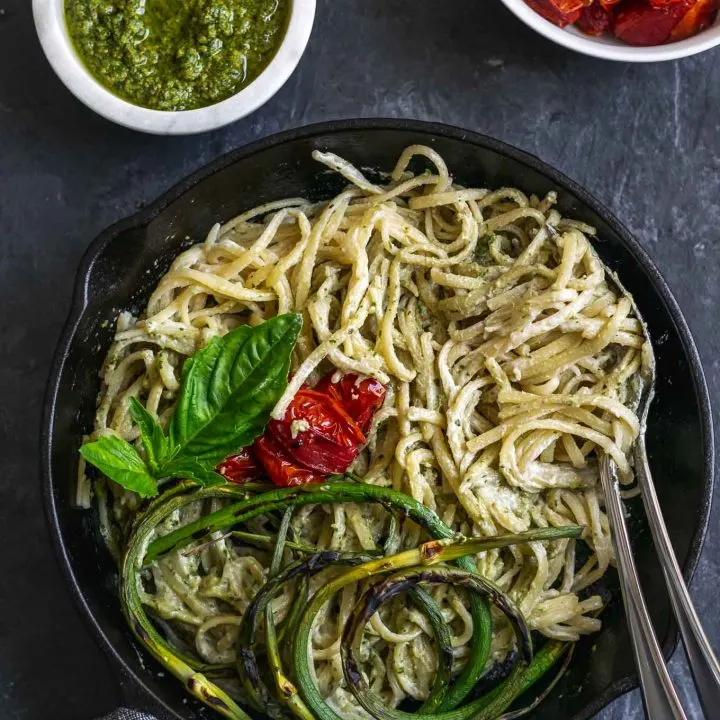 vegan garlic pesto alfredo pasta with grilled garlic scapes and roasted cherry tomatoes served with extra garlic scape pesto and tomatoes