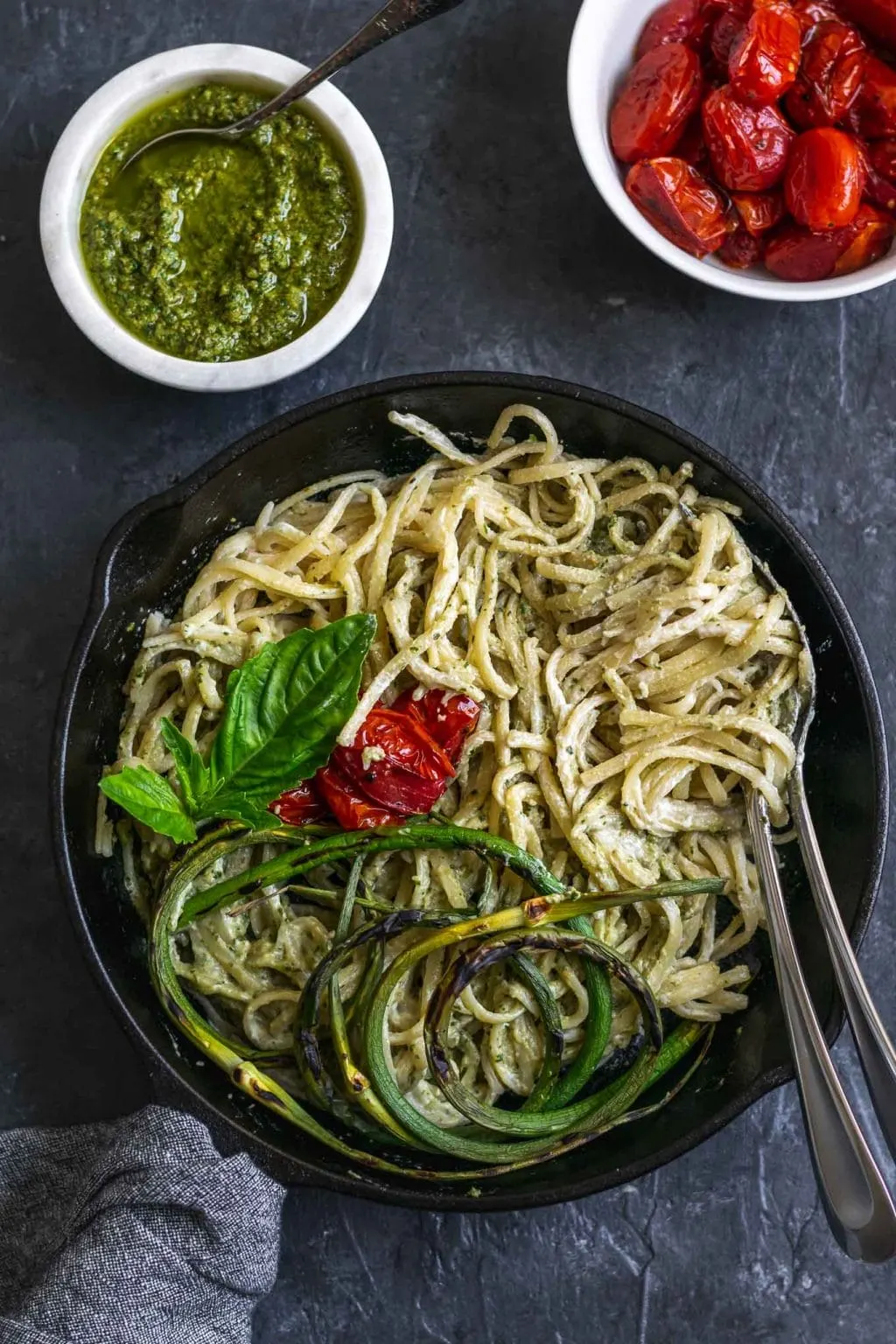 vegan garlic pesto alfredo pasta with grilled garlic scapes and roasted cherry tomatoes served with extra garlic scape pesto and tomatoes