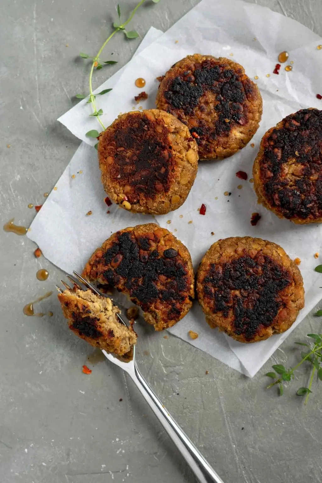 vegan tempeh maple breakfast sausage patties on parchment with a fork taking a portion out of one patty