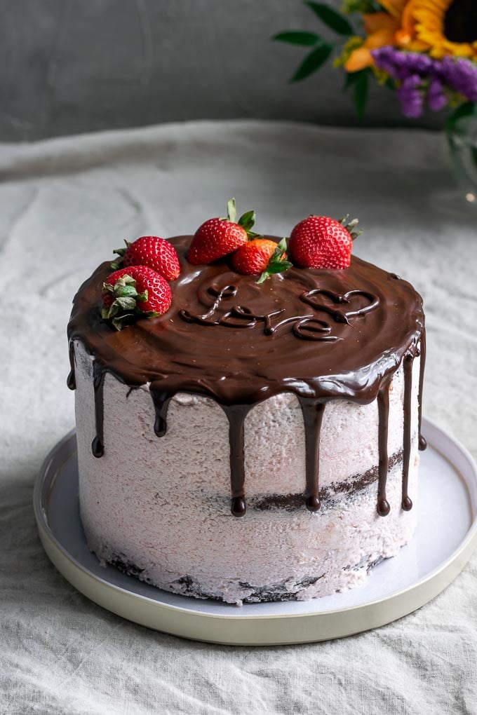 Chocolate cake with vegan aquafaba strawberry Italian meringue buttercream and a chocolate drip
