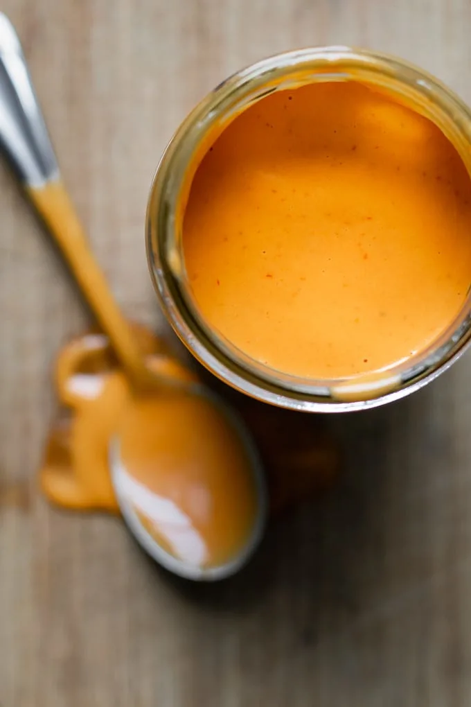 Creamy Mexican chipotle sauce made with aquafaba, overhead view of the sauce in a glass jar with a spoon to serve