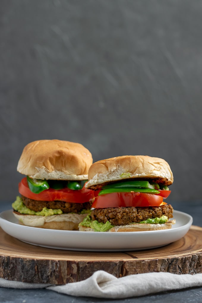 vegan curry seitan and black-eyed pea burgers with mashed avocado, sliced tomatoes, and jalapeños